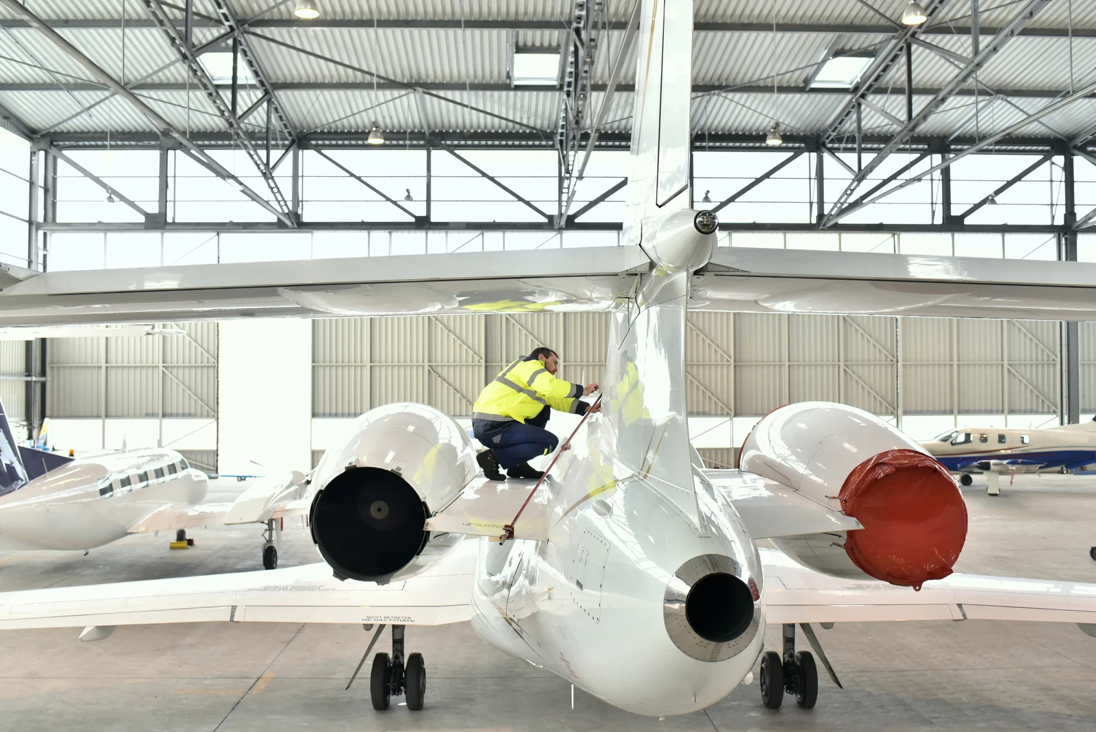 Illustrative licensed photograph of a professional caring for a private aircraft inside a hangar