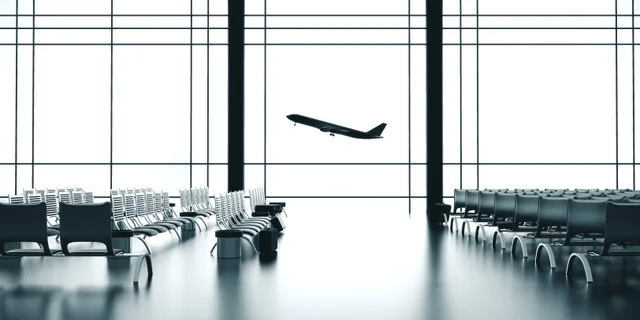 Asientos de una terminal y un avión despegando al otro lado de las ventanas. Imagen ilustrativa; no muestra este aeropuerto.