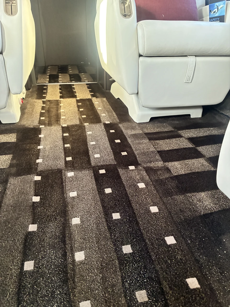 Patterned carpet between leather seats in a private aircraft cabin