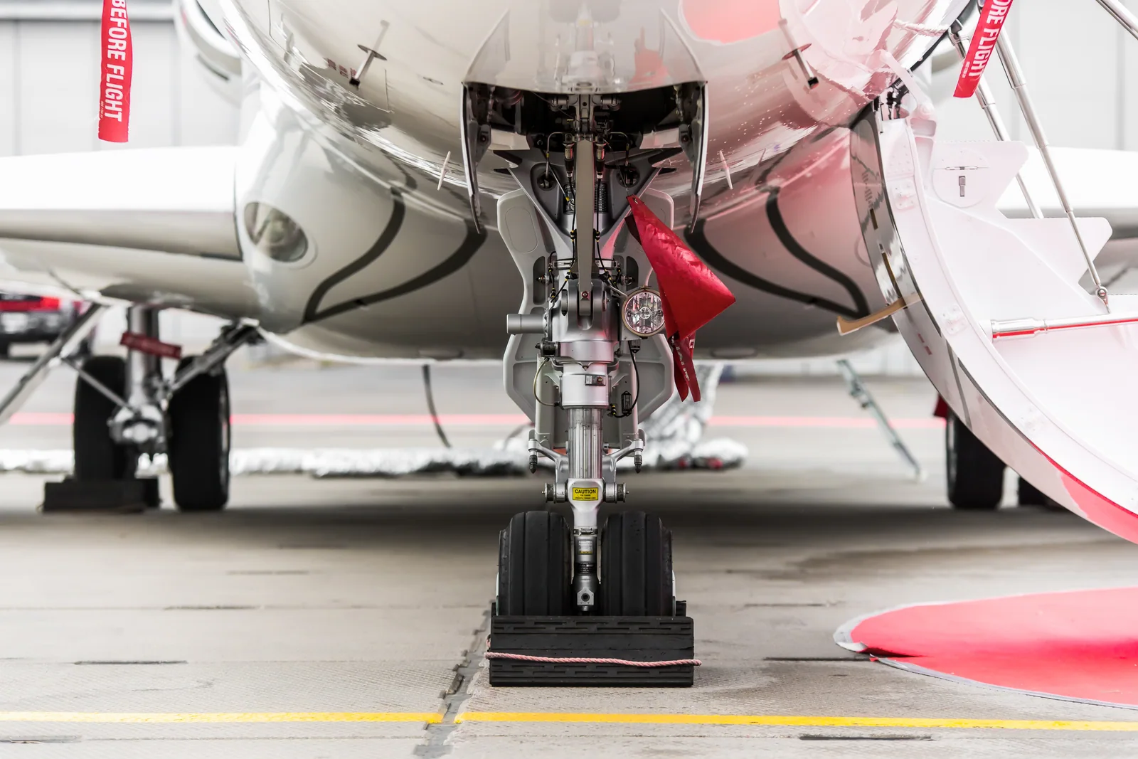Front landing gear and polished underside of a business jet in a hangar