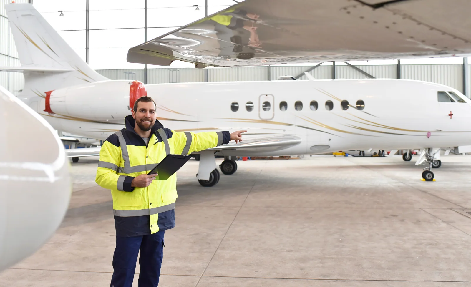Aviation professional with a clipboard beside a business jet in a hangar.